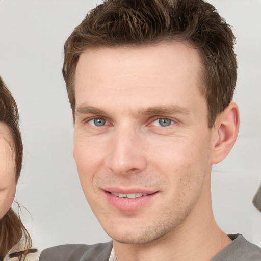 Joyful white young-adult male with short  brown hair and grey eyes