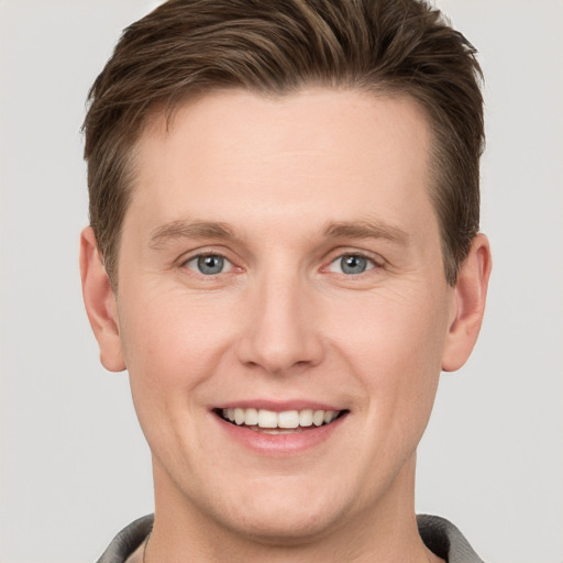 Joyful white young-adult male with short  brown hair and grey eyes