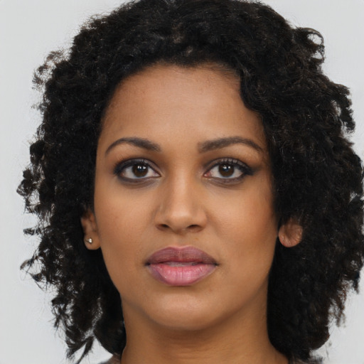 Joyful black young-adult female with long  black hair and brown eyes