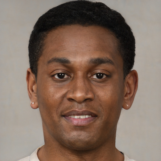 Joyful black young-adult male with short  brown hair and brown eyes
