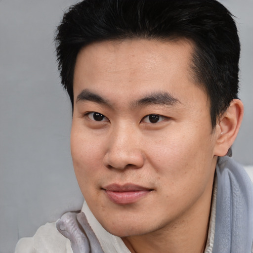 Joyful asian young-adult male with short  brown hair and brown eyes