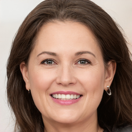 Joyful white adult female with long  brown hair and grey eyes