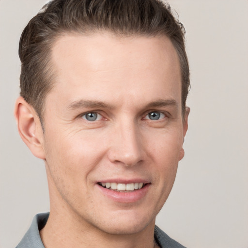 Joyful white young-adult male with short  brown hair and grey eyes