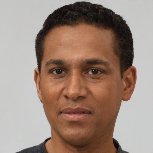 Joyful black adult male with short  black hair and brown eyes