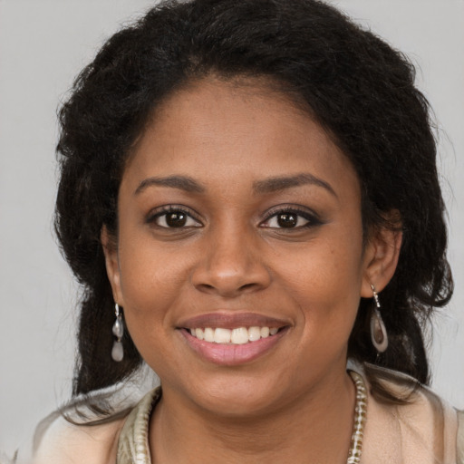Joyful black young-adult female with long  brown hair and brown eyes