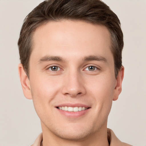 Joyful white young-adult male with short  brown hair and grey eyes