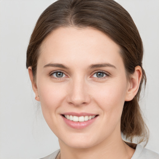 Joyful white young-adult female with medium  brown hair and grey eyes