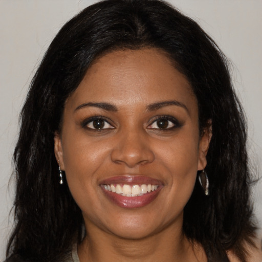 Joyful black young-adult female with long  brown hair and brown eyes