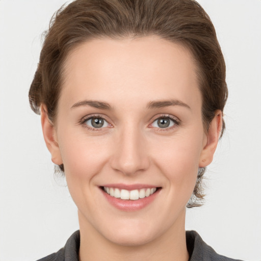 Joyful white young-adult female with medium  brown hair and grey eyes