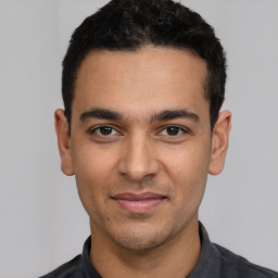 Joyful latino young-adult male with short  black hair and brown eyes