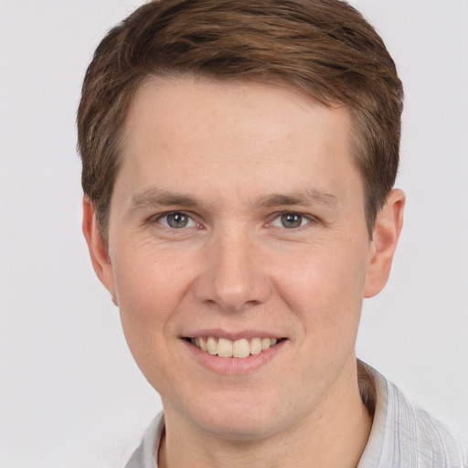 Joyful white young-adult male with short  brown hair and grey eyes