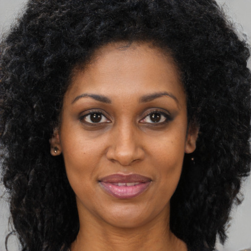 Joyful black young-adult female with long  brown hair and brown eyes