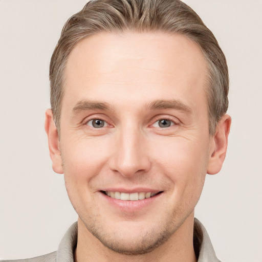 Joyful white young-adult male with short  brown hair and grey eyes