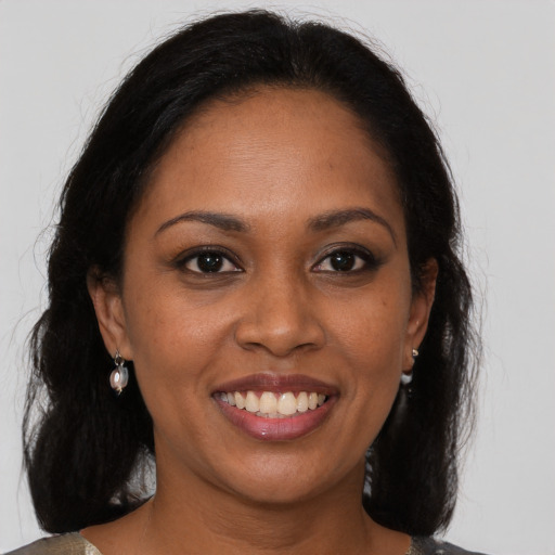 Joyful black young-adult female with long  brown hair and brown eyes