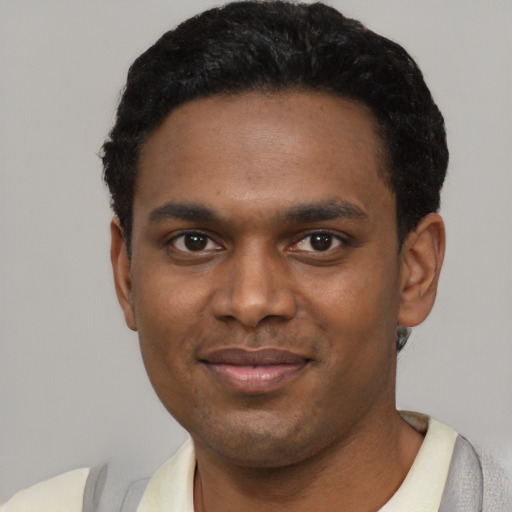Joyful black young-adult male with short  black hair and brown eyes