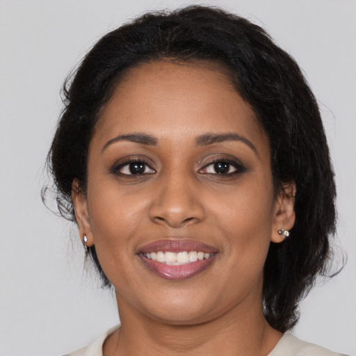 Joyful black young-adult female with medium  brown hair and brown eyes
