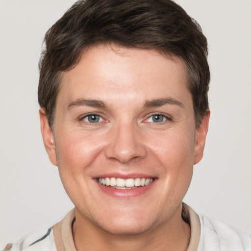 Joyful white young-adult male with short  brown hair and grey eyes