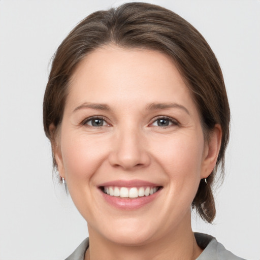 Joyful white young-adult female with medium  brown hair and grey eyes