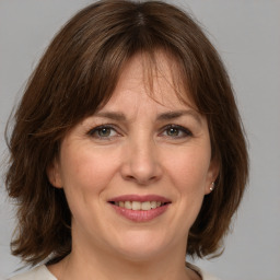 Joyful white adult female with medium  brown hair and grey eyes