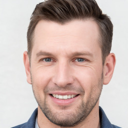 Joyful white young-adult male with short  brown hair and grey eyes