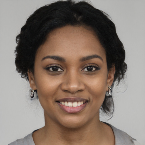 Joyful black young-adult female with long  black hair and brown eyes