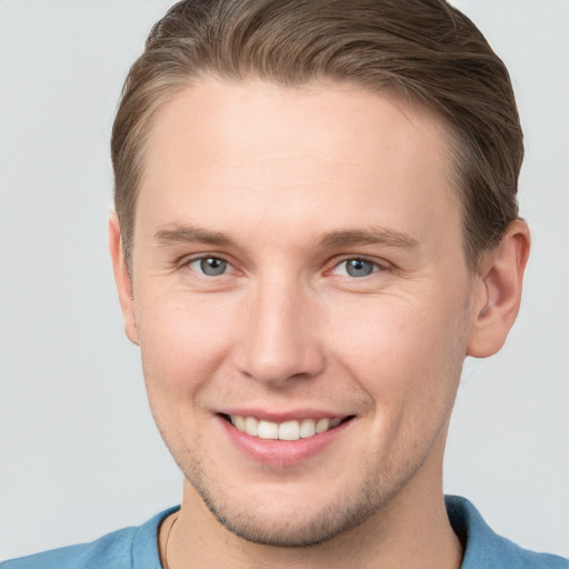 Joyful white young-adult male with short  brown hair and grey eyes