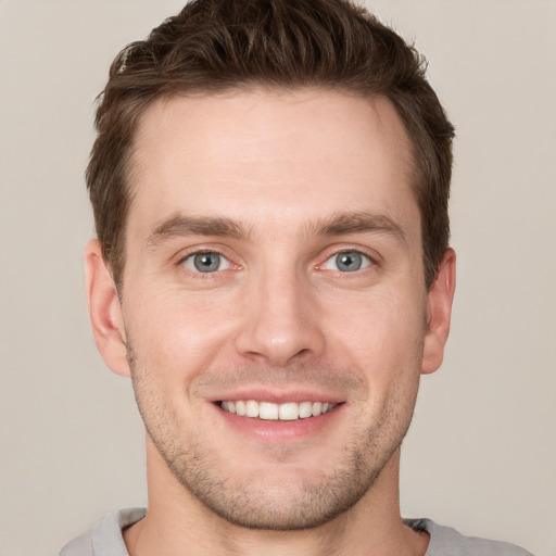 Joyful white young-adult male with short  brown hair and grey eyes