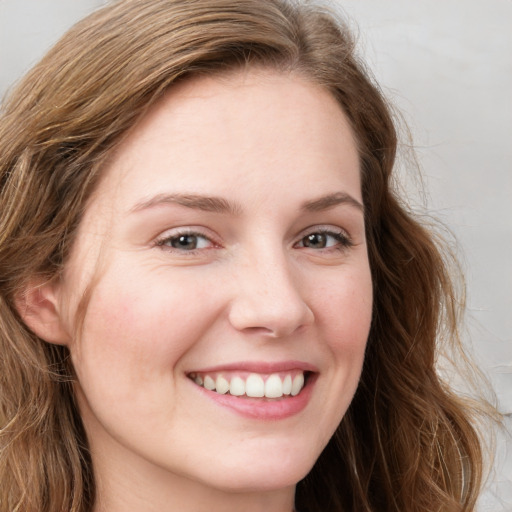 Joyful white young-adult female with long  brown hair and blue eyes