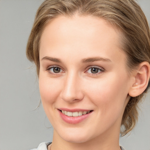 Joyful white young-adult female with medium  brown hair and grey eyes