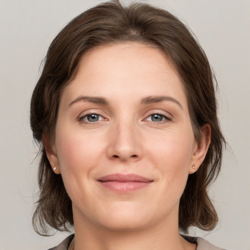 Joyful white young-adult female with medium  brown hair and grey eyes