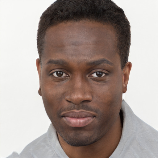 Joyful black young-adult male with short  brown hair and brown eyes