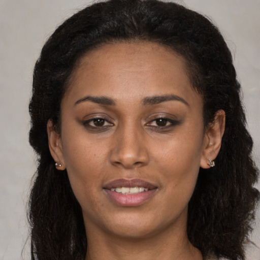 Joyful black young-adult female with long  brown hair and brown eyes