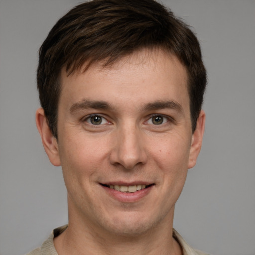 Joyful white young-adult male with short  brown hair and grey eyes