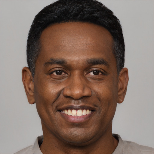 Joyful black young-adult male with short  black hair and brown eyes
