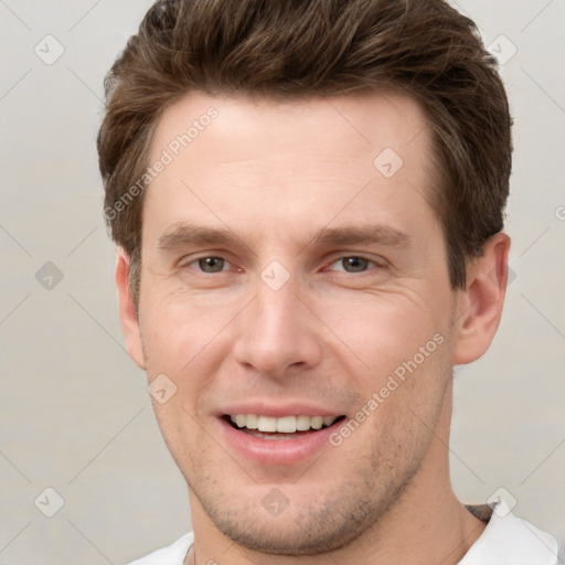 Joyful white young-adult male with short  brown hair and grey eyes