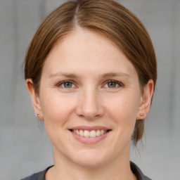 Joyful white young-adult female with medium  brown hair and grey eyes