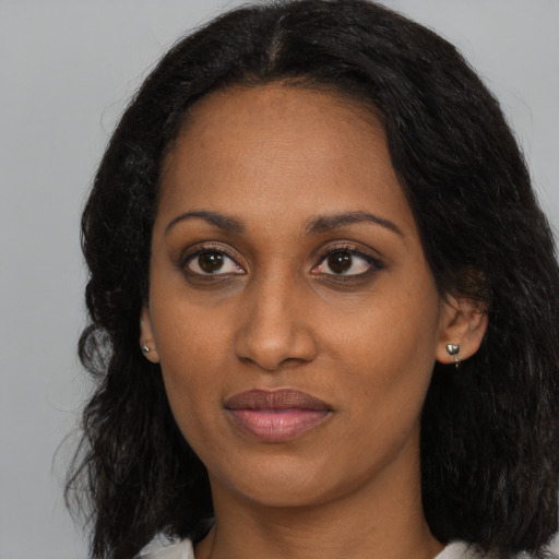 Joyful black young-adult female with long  brown hair and brown eyes