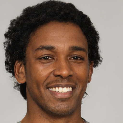 Joyful black young-adult male with short  brown hair and brown eyes