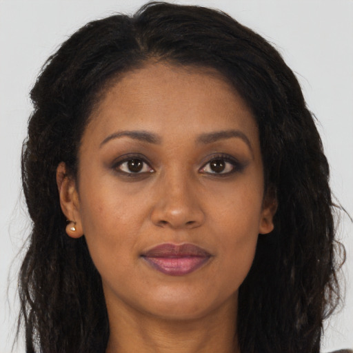 Joyful black young-adult female with long  brown hair and brown eyes