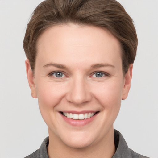 Joyful white young-adult female with short  brown hair and grey eyes