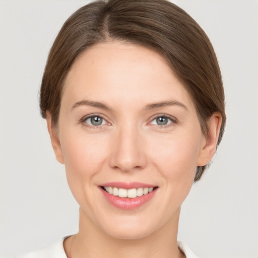 Joyful white young-adult female with medium  brown hair and grey eyes