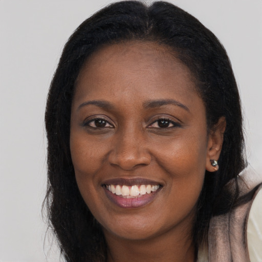 Joyful black young-adult female with long  brown hair and brown eyes
