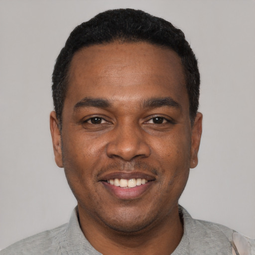 Joyful black young-adult male with short  black hair and brown eyes