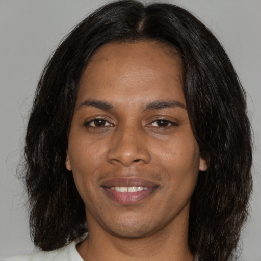 Joyful black young-adult female with long  brown hair and brown eyes