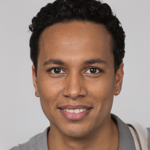 Joyful black young-adult male with short  brown hair and brown eyes