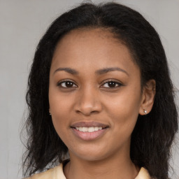 Joyful black young-adult female with long  brown hair and brown eyes