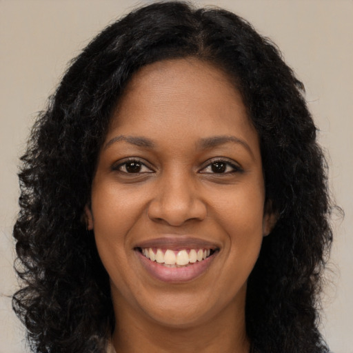 Joyful black young-adult female with long  brown hair and brown eyes