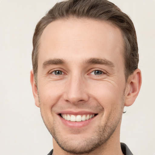 Joyful white young-adult male with short  brown hair and grey eyes