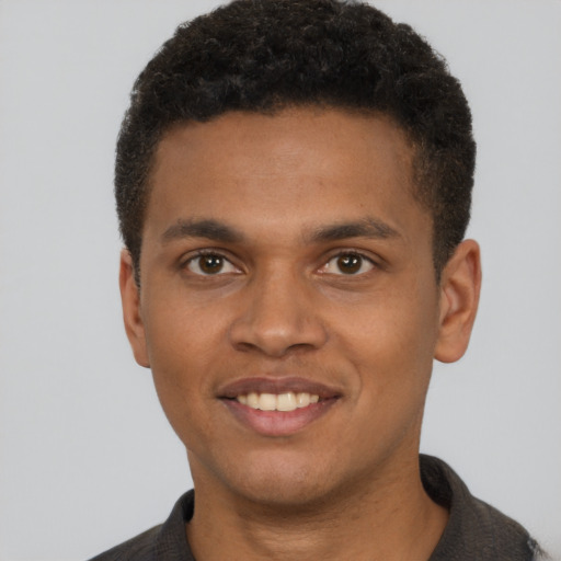 Joyful black young-adult male with short  brown hair and brown eyes