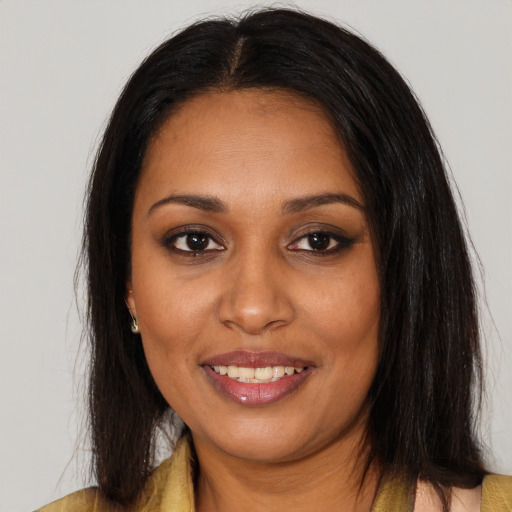 Joyful black young-adult female with long  brown hair and brown eyes
